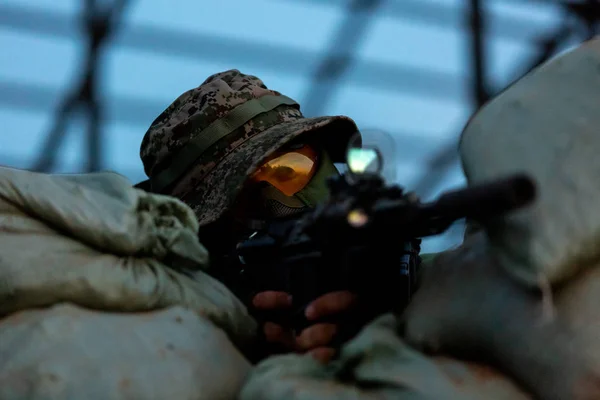 Sniper armé d'un fusil de sniper de gros calibre, tirant sur des cibles ennemies à distance de tir depuis un abri, assis dans une embuscade. Vue de face — Photo