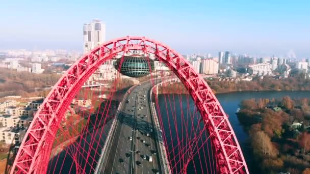 Flygfoto över den ikoniska landmärke som är pittoreskt bro som korsar floden Moskva i Moskva. Bilar trafik på snedkabelbro av röd färg på dagtid. 4k. — Stockvideo