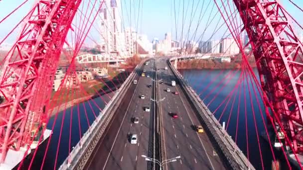 Vista aérea del emblemático monumento que es el pintoresco puente que cruza el río Moscú en Moscú. Tráfico de coches en el puente de cable de color rojo durante el día. 4K . — Vídeos de Stock