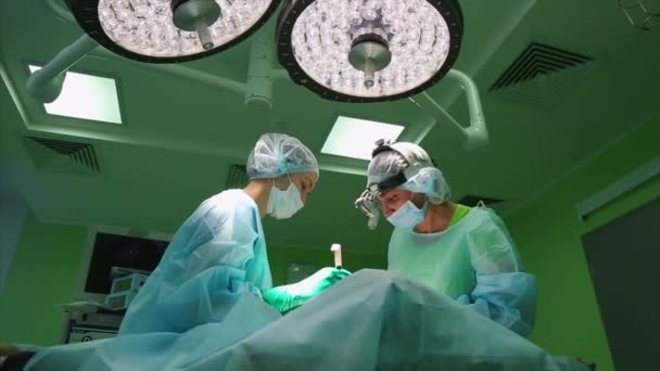 Cirurgião e equipe cirúrgica estão realizando cirurgia estética em mamas no centro cirúrgico do hospital. Aumento da mama. Mamoplastia. Ampliação mamária. Detalhe da cirurgia . — Vídeo de Stock