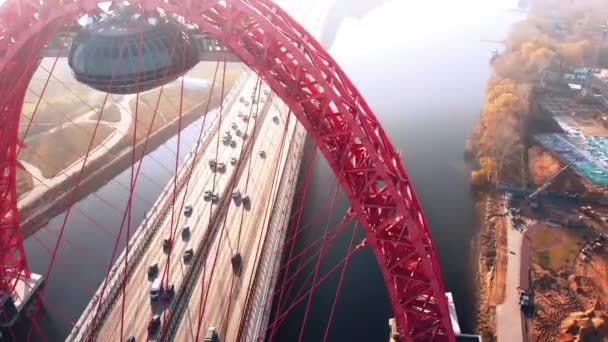 Luftaufnahme des symbolträchtigen Wahrzeichens, der malerischen Brücke, die den Moskauer Fluss in Moskau überquert. Der Autoverkehr auf der Schrägseilbrücke ist tagsüber rot gefärbt. 4k. — Stockvideo