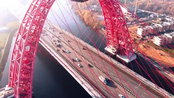 Vista aérea del emblemático monumento que es el pintoresco puente que cruza el río Moscú en Moscú. Tráfico de coches en el puente de cable de color rojo durante el día. 4K . — Vídeos de Stock