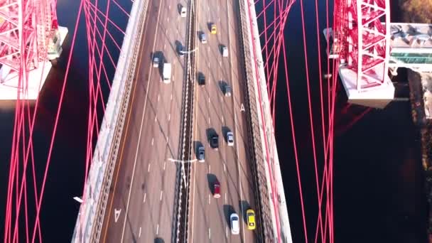 Αεροφωτογραφία από το εμβληματικό ορόσημο που είναι γραφική γέφυρα που διασχίζει τον ποταμό Μόσχα στη Μόσχα. Κυκλοφορία αυτοκινήτων στο καλώδιο-μένοντη γέφυρα του κόκκινου χρώματος στο χρόνο ημέρας. 4k. — Αρχείο Βίντεο