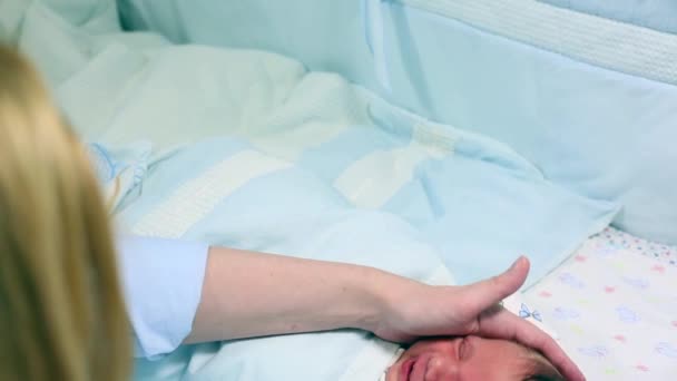 Close up de um bebê recém-nascido chorando em seu berço e sua mãe tentando acalmá-lo — Vídeo de Stock