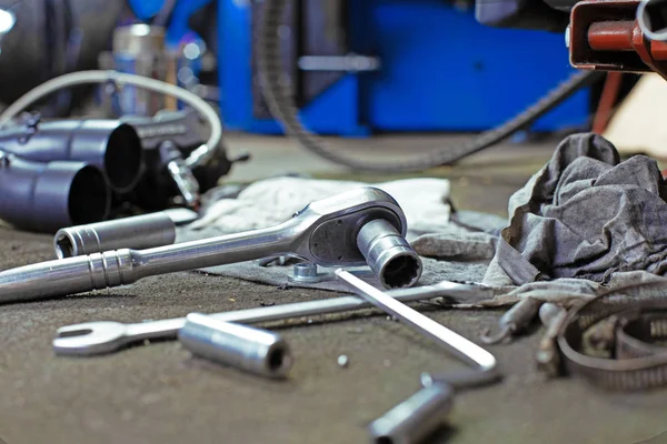 Atölye onarılan eski bisiklet ya da motosiklet motoru yakınındaki bir katta vida ve anahtar satırı araçları. Ekipman endüstriyel sahne — Stok fotoğraf
