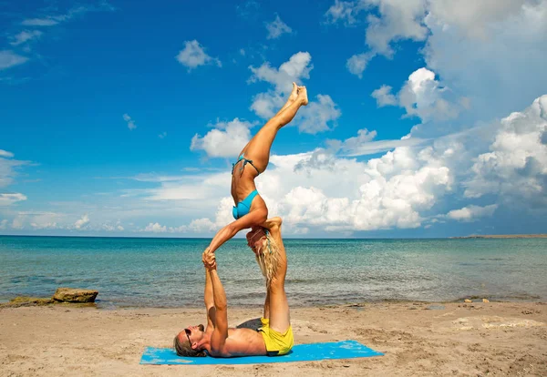 Two young man and woman on beach doing fitness yoga exercise together. Acroyoga element for strength and balance — Stock Photo, Image