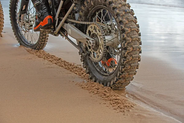 Motocykl kola nechat stopy ve vlhkém písku na pláži — Stock fotografie