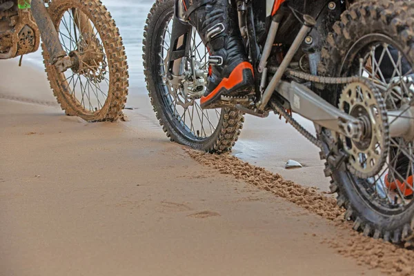 motorcycle wheels leave footprints in the wet sand on the beach