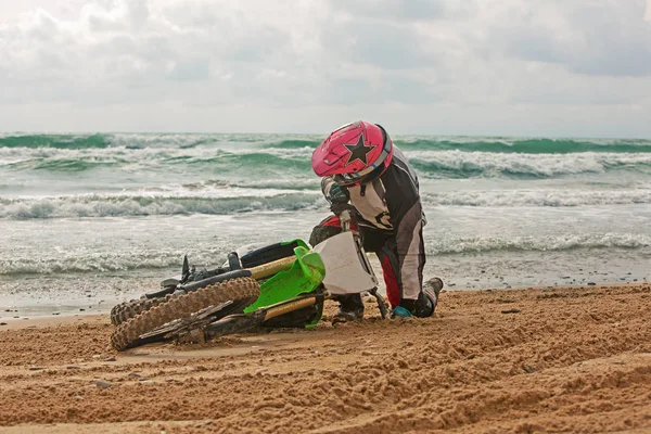 Motociclista caduto su una moto sulla spiaggia sullo sfondo del mare — Foto Stock