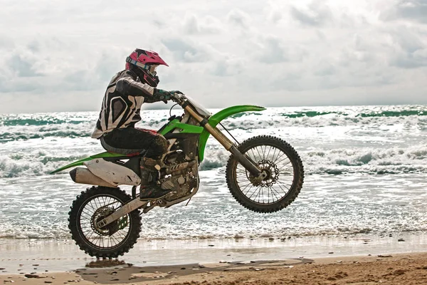 Motociclista en un traje de protección monta una motocicleta en el mar, salpicaduras vuelan desde debajo de las ruedas . —  Fotos de Stock