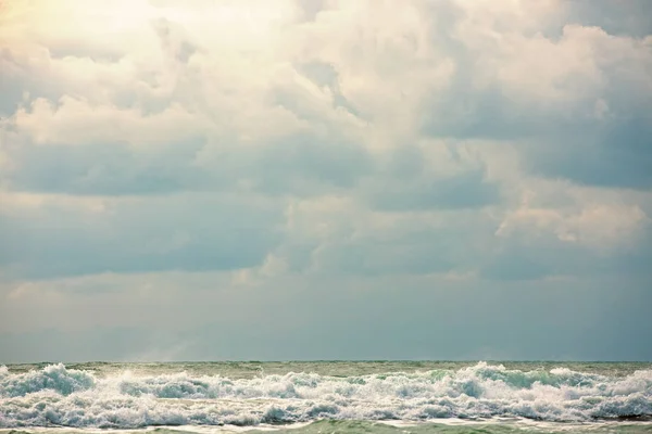 Paisaje marino tormentoso con cielo nublado y olas de mar sobre arena marrón húmeda. Agua de mar verde con olas de espuma blanca y silueta oscura de la embarcación en horizonte horizonte. Mar vacaciones escena . —  Fotos de Stock
