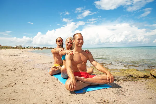 Deux jeunes hommes et femmes sur la plage faisant des exercices de yoga de fitness ensemble. Élément Acroyoga pour la force et l'équilibre — Photo