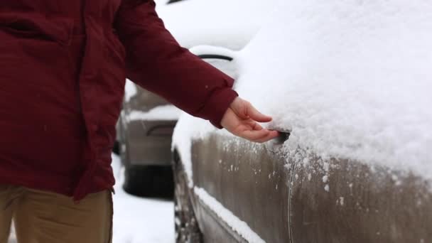 Seorang pria membersihkan salju dari mobil dan membuka pintu mobil — Stok Video