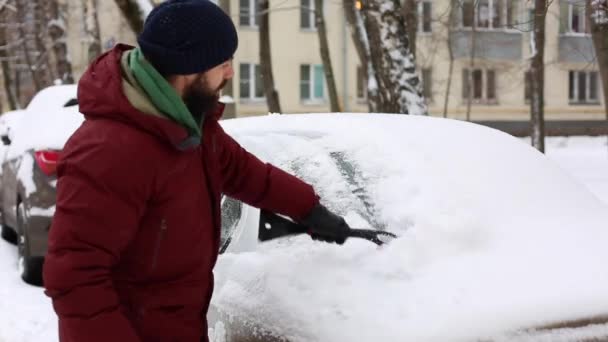 Чоловік прибирає сніг з машини пензлем у житловому будинку район — стокове відео