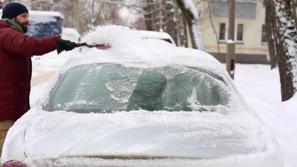 Uomo pulizia neve da auto con spazzola nel quartiere casa vivente — Video Stock