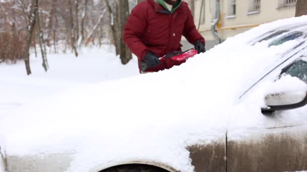 Hombre limpieza de nieve de coche con cepillo en el barrio de la casa de estar — Vídeo de stock