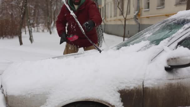 Hombre limpieza de nieve de coche con cepillo en el barrio de la casa de estar — Vídeo de stock