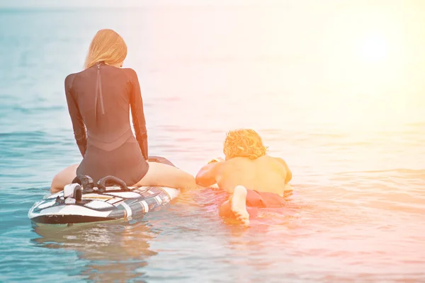 Surfistas en la playa- Pareja sonriente de surfistas nadando en el mar y divirtiéndose en verano. Deporte extremo y concepto de vacaciones —  Fotos de Stock