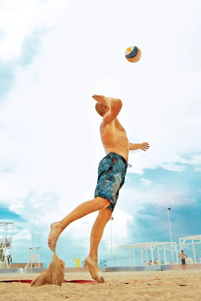 Volleybollspelare beach är en manlig idrottsman volleybollspelare redo att tjäna bollen på stranden. — Stockfoto