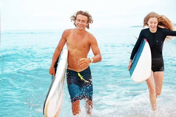 Σέρφερ σε την παραλία-χαμογελώντας ζευγάρι των surfers περπάτημα στην παραλία και έχοντας διασκέδαση το καλοκαίρι. Ακραία έννοια άθλημα και διακοπές — Φωτογραφία Αρχείου