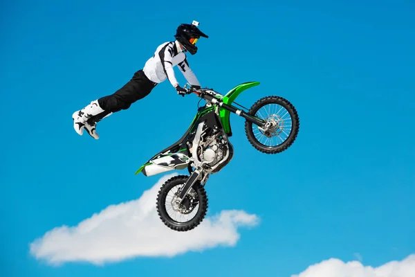 Corredor en motocicleta participa en motocross cross-country en vuelo, salta y despega en trampolín contra el cielo. Concepto de descanso extremo activo . —  Fotos de Stock