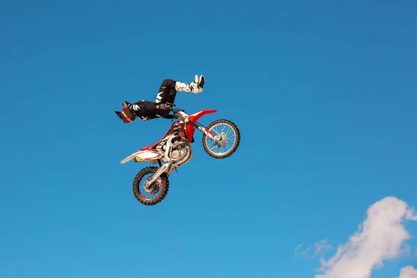 Corredor en motocicleta participa en motocross cross-country en vuelo, salta y despega en trampolín contra el cielo. Concepto de descanso extremo activo . —  Fotos de Stock