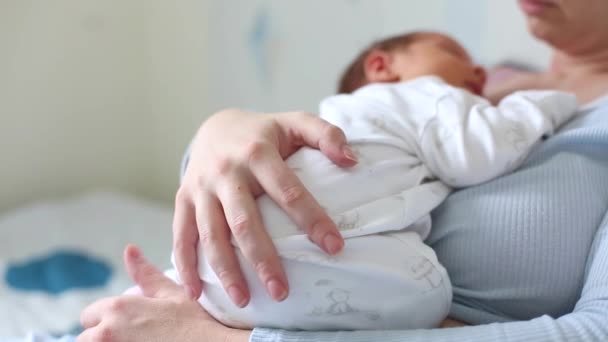 Jovem mãe bonita segurando seu bebê bonito que está dormindo em seu peito de mães em casa — Vídeo de Stock
