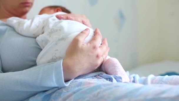 Young beautiful mother holding her cute baby who is sleeping on her moms chest at home — Stock Video