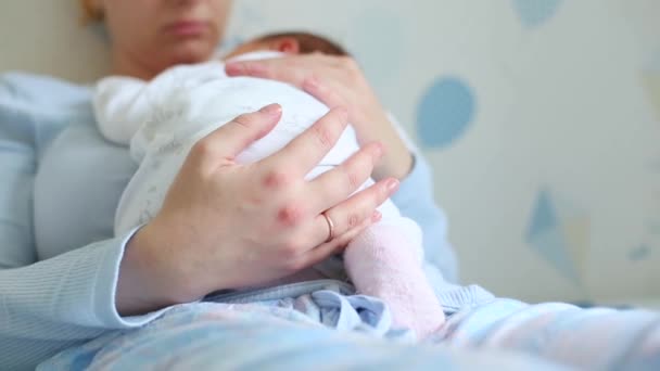 Young beautiful mother holding her cute baby who is sleeping on her moms chest at home — Stock Video