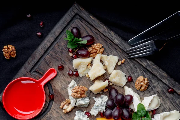 Cheese plate served with grapes, honey and nuts on a wooden background. Various types of cheese — Stock Photo, Image