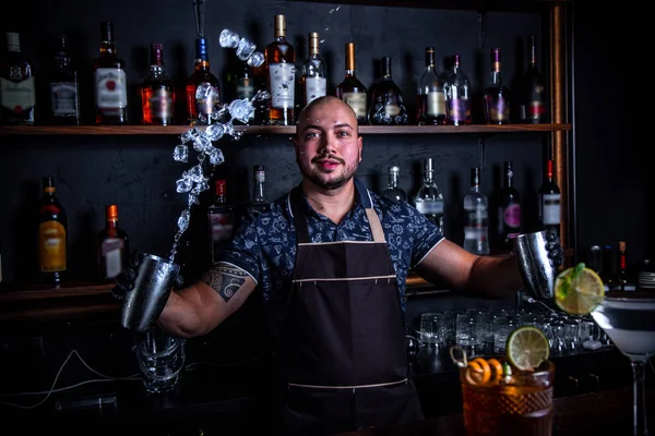 The barman juggler throws up an ice for cocktail at bar — Stock Photo, Image