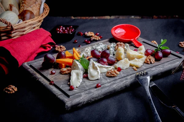 Cheese plate served with grapes, honey and nuts on a wooden background. Various types of cheese — Stock Photo, Image