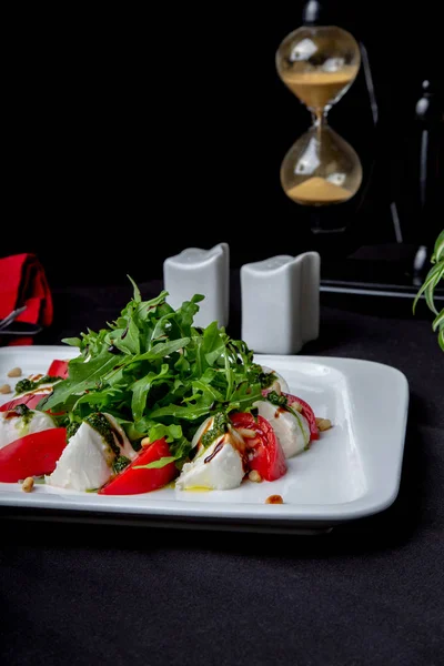 Caprese İtalyanca ya Akdeniz salatası. Domates mozzarella fesleğen yaprakları ve zeytinyağı siyah masada. — Stok fotoğraf