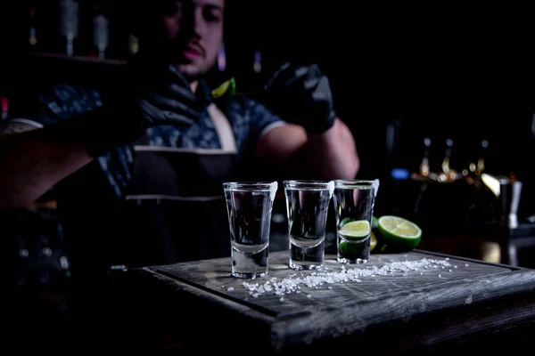 aperitif with friends in the bar, three glasses of alcohol with lime and salt for decoration. Tequila shots, selective focus