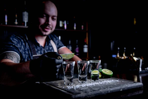 aperitif with friends in the bar, three glasses of alcohol with lime and salt for decoration. Tequila shots, selective focus