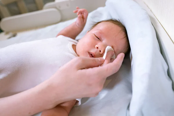 Moeder reinigen van de ogen van een pasgeboren baby met katoen strip — Stockfoto