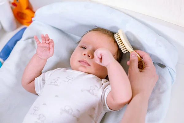 Mor kamma håret för hennes nyfödda baby. Begreppet nyfödda vård. — Stockfoto