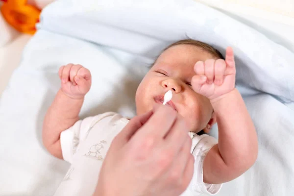 Hygiene für Neugeborene. Mutter reinigt Baby-Nase mit Wattestäbchen, Nahaufnahme — Stockfoto