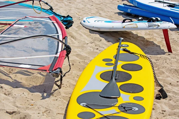 Tabuleiro de windsurf com vela deitada na areia — Fotografia de Stock