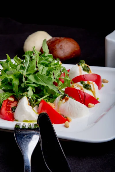 Ensalada Caprese italiana o mediterránea. Tomate mozzarella hojas de albahaca y aceite de oliva sobre mesa negra . — Foto de Stock