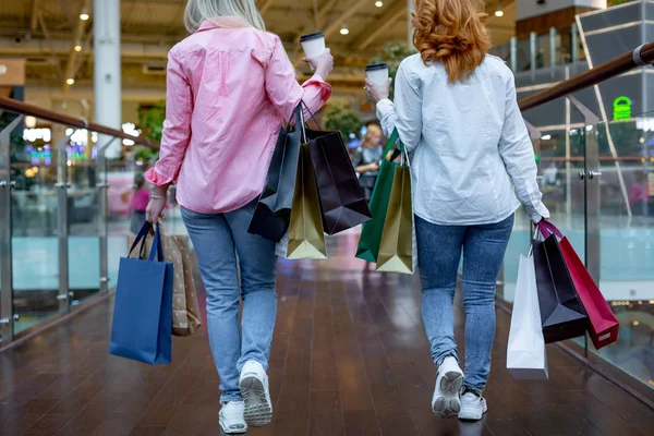 Felice giovani donne con shopping bags godendo nello shopping, le ragazze si stanno divertendo con i loro acquisti. vista posteriore. Consumismo e stile di vita — Foto Stock