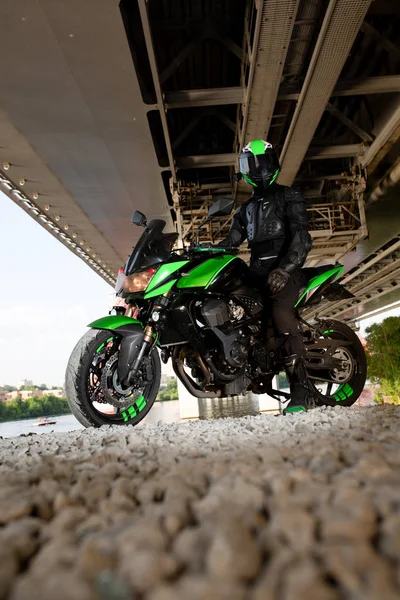 Motorcyclist stop under the bridge over the road waiting for rain to stop