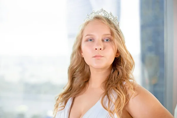 Hermosa novia discapacitada posando en una silla de ruedas sobre el fondo de una ventana panorámica que está sonriendo a la cámara, discapacidad superando el concepto — Foto de Stock