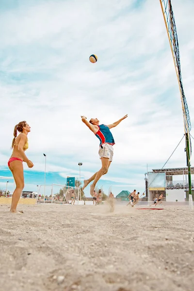 Skupina přátel hrát hru s míčem na pláži na pozadí slunce moře — Stock fotografie