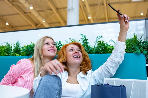 Dwaj przyjaciele zadowolony jest selfie biorąc podczas robienia zakupów w centrum handlowym. — Zdjęcie stockowe