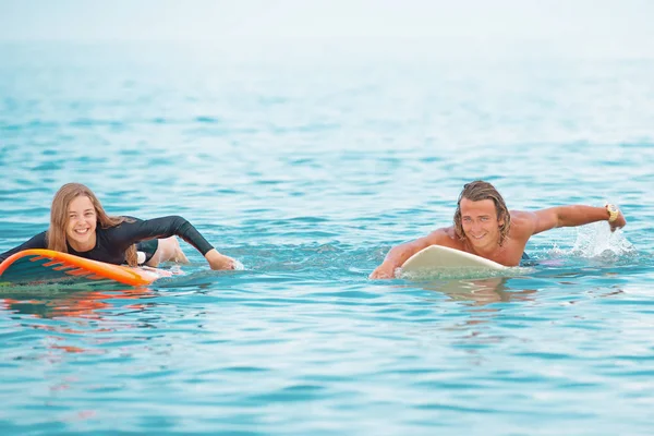 Σέρφερ σε την παραλία-χαμογελώντας ζευγάρι των surfers κολύμπι και διασκέδαση το καλοκαίρι. Ακραία έννοια άθλημα και διακοπές — Φωτογραφία Αρχείου