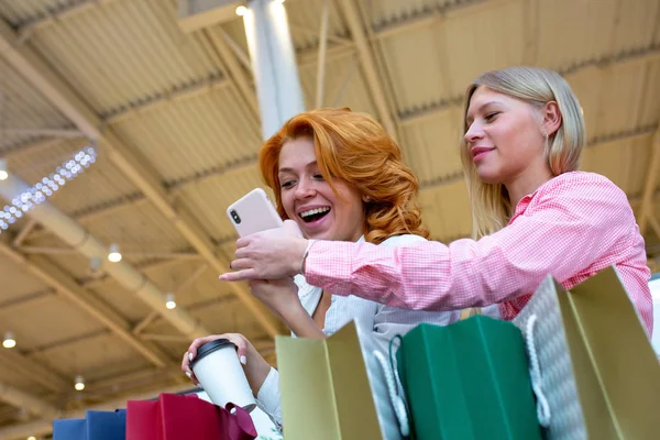 Két boldog női barátok használ mozgatható telefon, bevásárlóközpont, kávézó — Stock Fotó