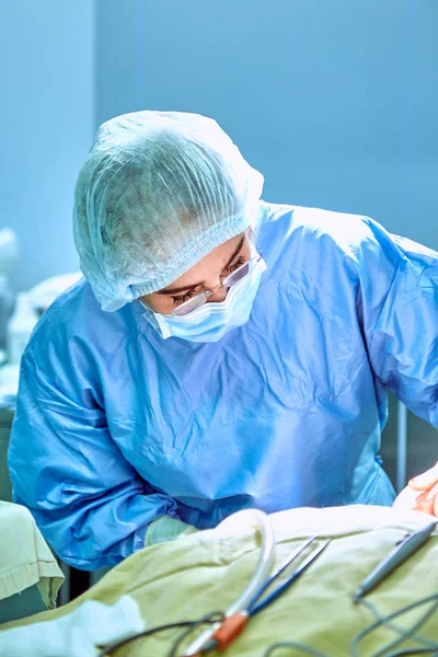 Close up portrait of young female surgeon doctor wearing protective mask and hat during the operation. Healthcare, medical education, surgery concept — Stock Photo, Image