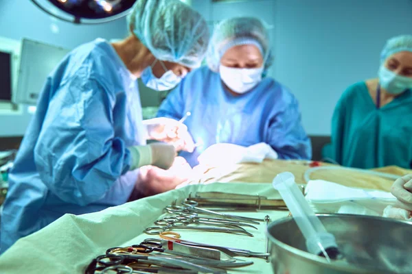 Dienblad met chirurgische instrumenten op de voorgrond in de operatiekamer, plastische chirurgie - kin vermindering augmentatie onderkin verwijderen cosmetische operatie concept. — Stockfoto