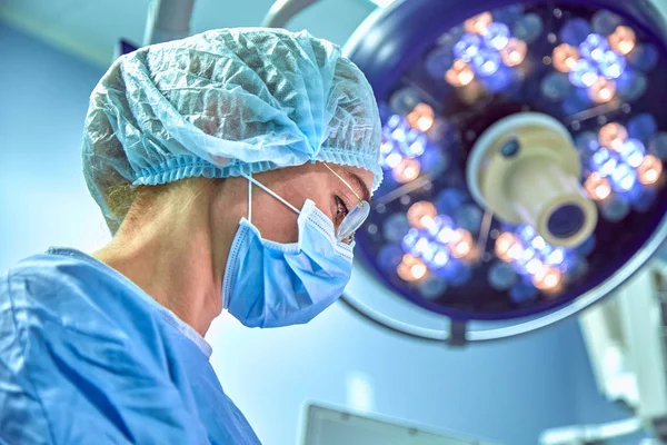 Portrait en gros plan d'une jeune chirurgienne portant un masque protecteur et un chapeau pendant l'opération. Soins de santé, éducation médicale, concept de chirurgie — Photo